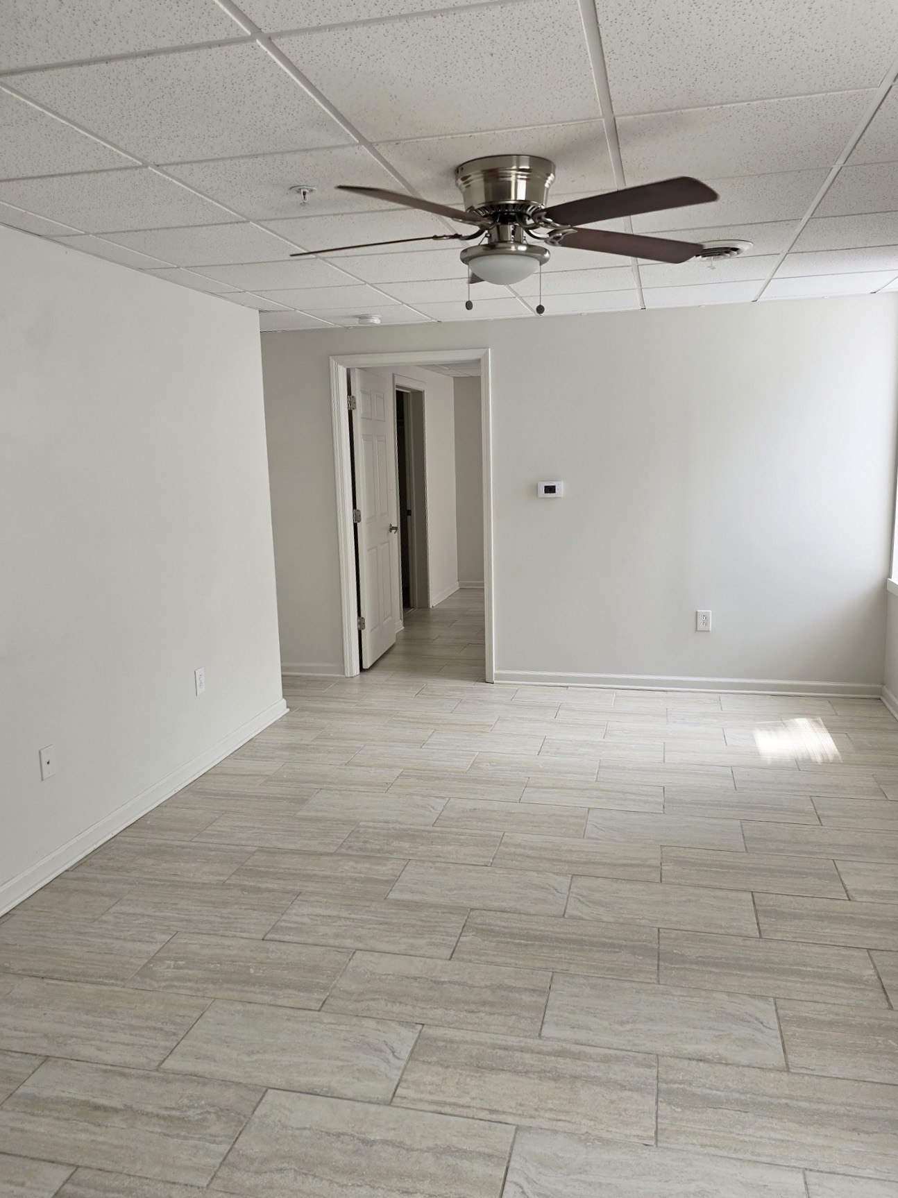 A room with a ceiling fan and tile flooring.